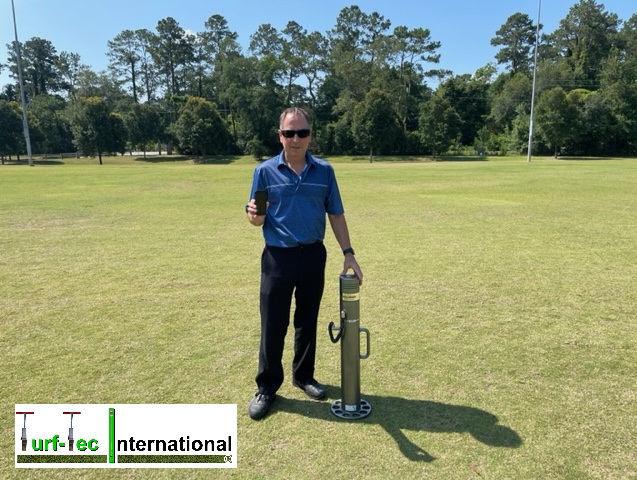 John Mascaro, President of Turf-Tec Internationals is standing on grass showcasing t=Deltec Equipment's Fieldtester.